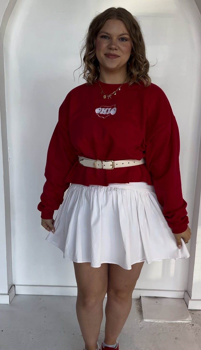 Woman wearing a red Ohio embroidered crewneck sweatshirt featuring a white Ohio script design.