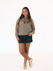 Woman wearing a beige sweatshirt with graphic design and a denim skirt on a white background