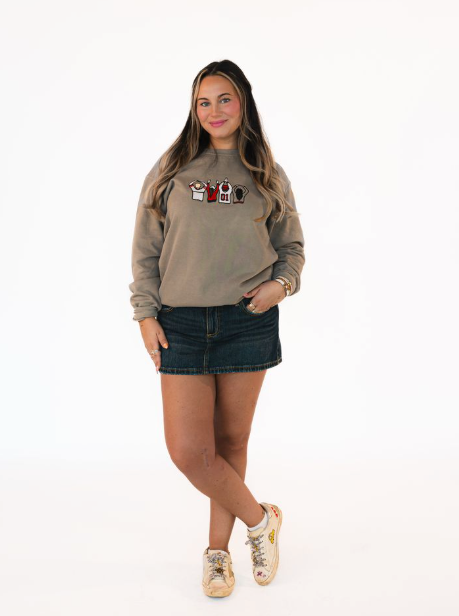 Woman wearing a beige sweatshirt with graphic design and a denim skirt on a white background