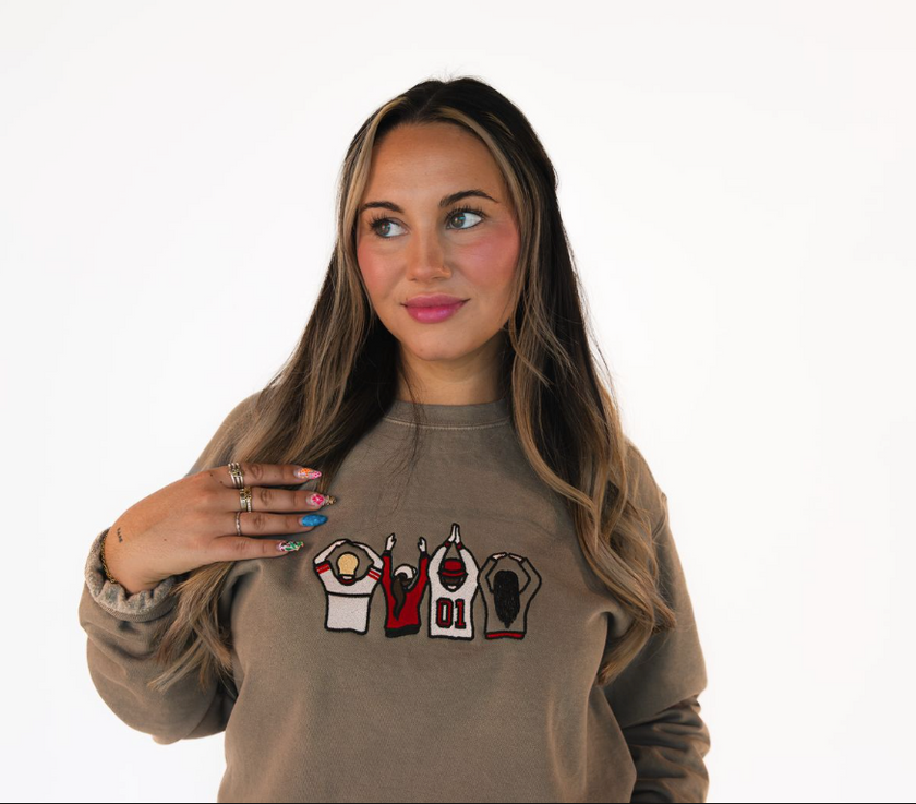 Woman wearing a brown sweatshirt with graphic designs on a white background