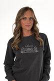 Close-up portrait of a woman looking away, wearing a charcoal gray crewneck sweatshirt featuring a fine white embroidered outline of the Ohio Stadium and script 
