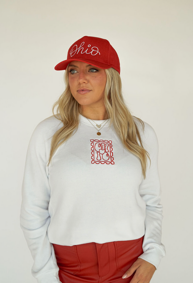 Woman wearing a red Ohio embroidered trucker hat with white script lettering.