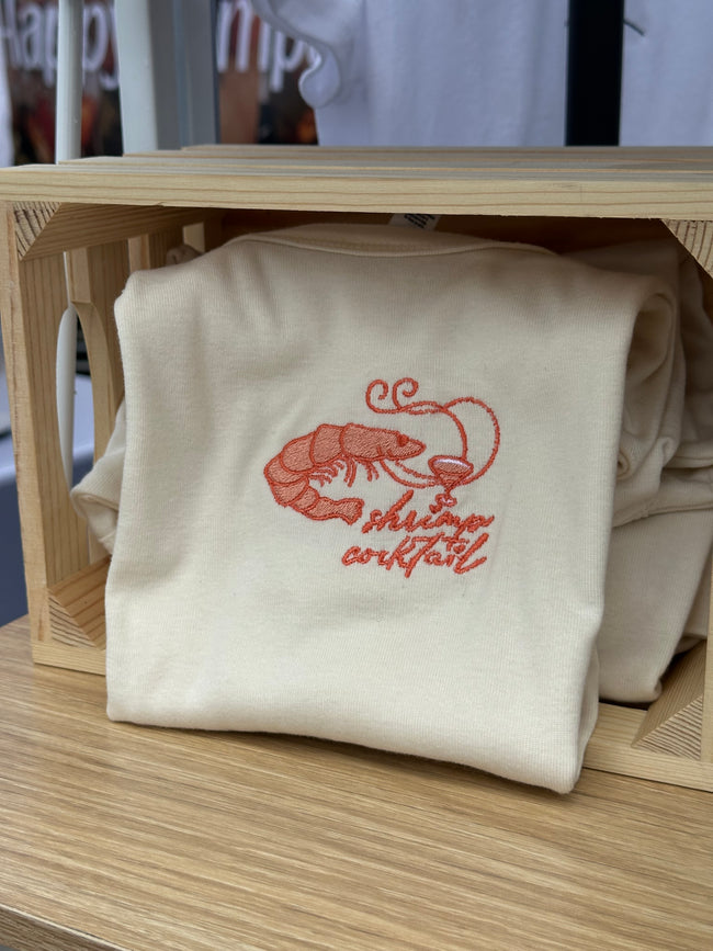 Cream baby tee or tank with coral embroidered shrimp and cocktail design on the chest.