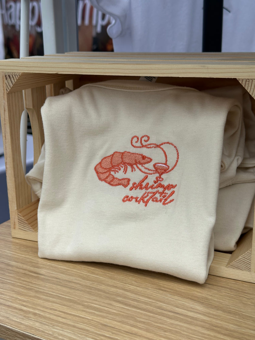 Cream baby tee or tank with coral embroidered shrimp and cocktail design on the chest.