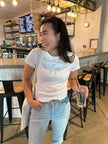 Model wearing the Simple Saturdays white and blue embroidered baby tee with casual denim.