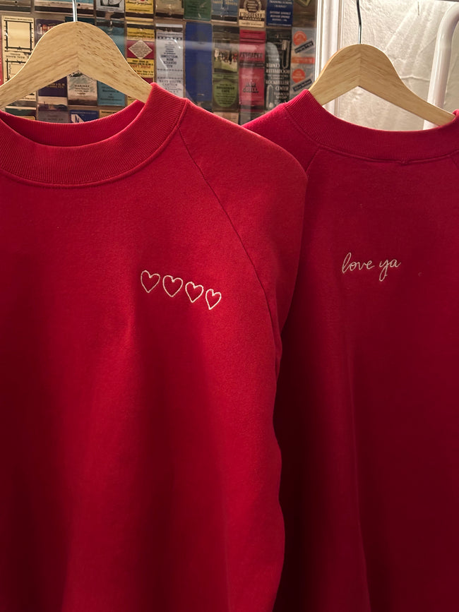 Close-up of the minimalist Valentine's embroidery stitched on the red crewneck.