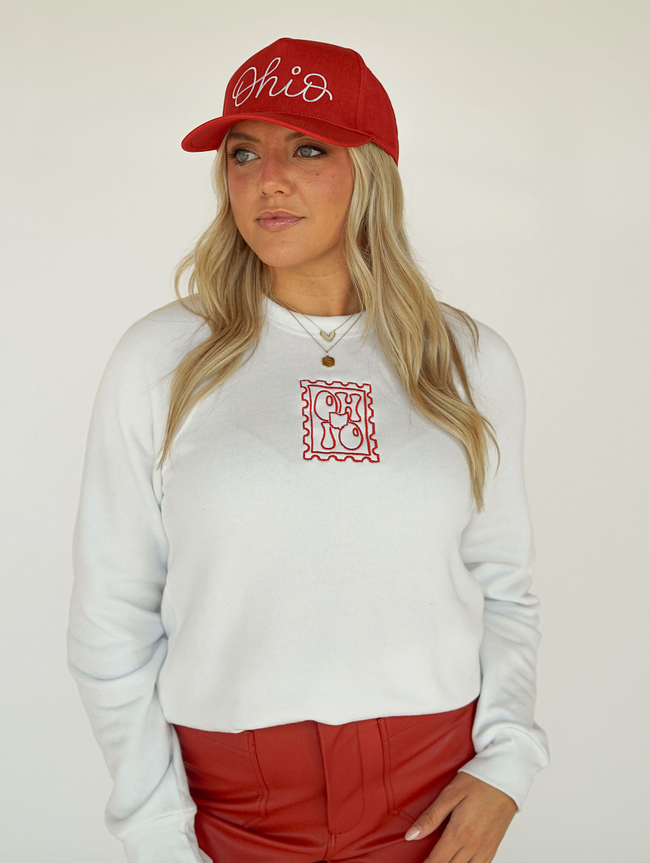 Model wearing a white embroidered Ohio stamp crewneck sweatshirt with casual denim.