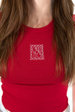 A close-up of a person wearing a bright red ribbed crop top with a small white outlined square graphic on the chest.