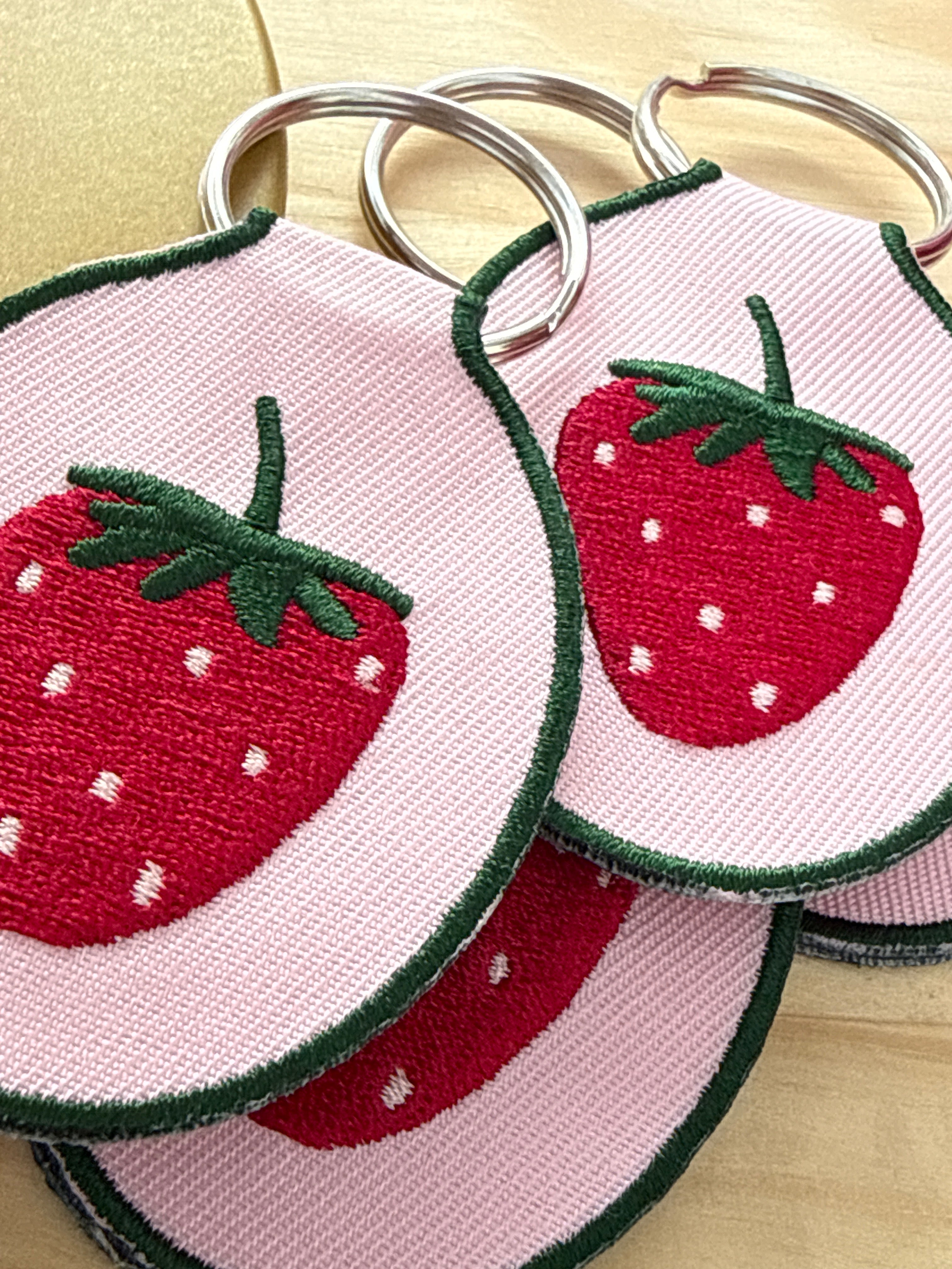 Embroidered strawberry keychain with a gold metal key ring.