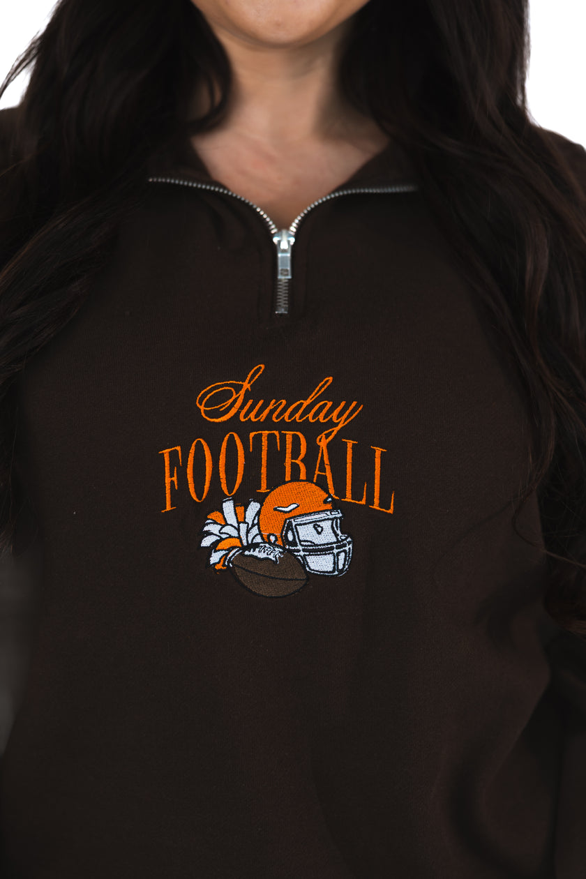 Close-up of a brown Sunday Football embroidered quarter zip featuring orange 