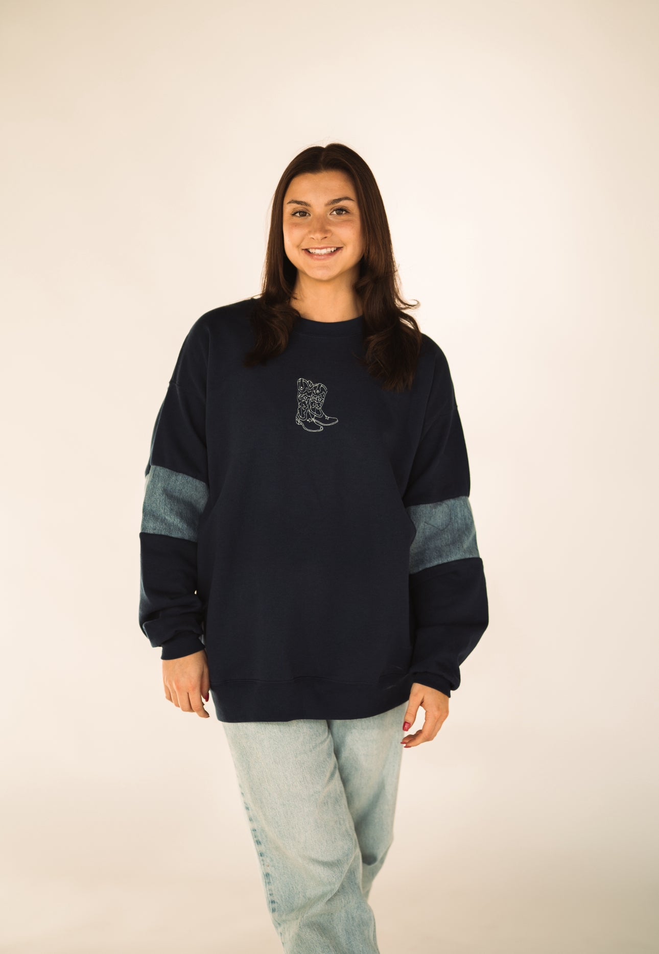 Model wearing crewneck sweatshirt featuring handcrafted reclaimed denim panels inspired by Western style.