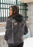 Back view of a woman wearing a black color-block denim jacket with oversized fit and contrasting denim panels.