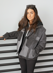Woman wearing a black color-block denim jacket with oversized fit and front patch pockets.
