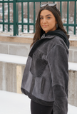 Side view of a woman wearing a black color-block denim jacket with oversized fit.