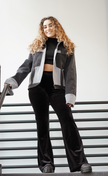Full-body view of a woman wearing a black color-block denim jacket with oversized fit.