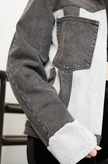 Close-up of a black color-block denim jacket with contrasting gray denim panels and front patch pocket.