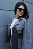Woman wearing a gray color-block denim jacket with contrasting black denim panels and oversized fit.