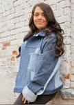 Side view of a woman wearing a light wash color-block denim jacket with oversized fit.