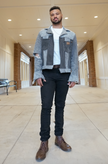 Full-body view of a man wearing a gray color-block denim jacket with contrasting black denim panels.