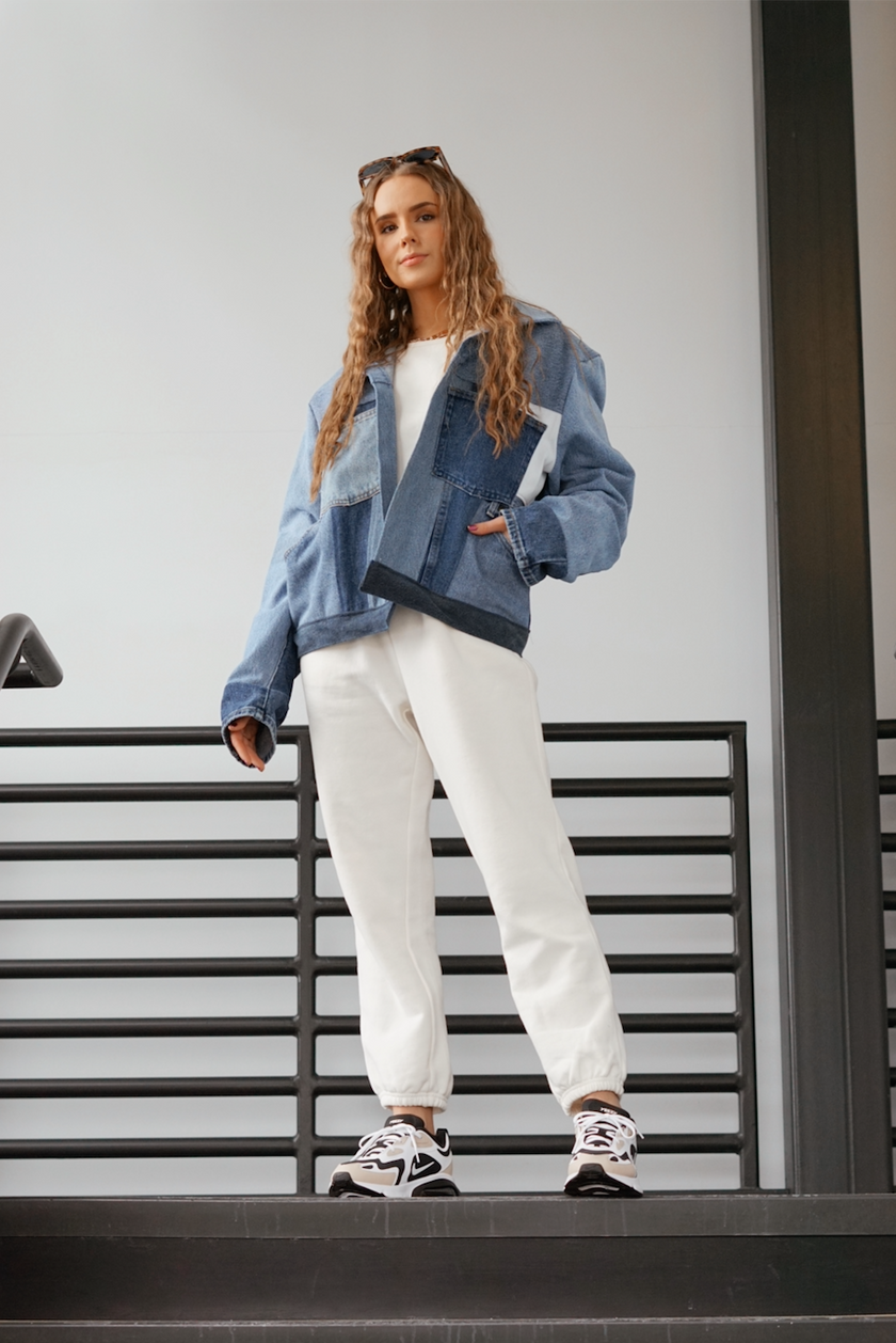 Woman wearing a light wash color-block denim jacket with oversized fit.