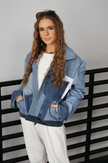 Woman wearing a light wash color-block denim jacket with front patch pockets and oversized fit.